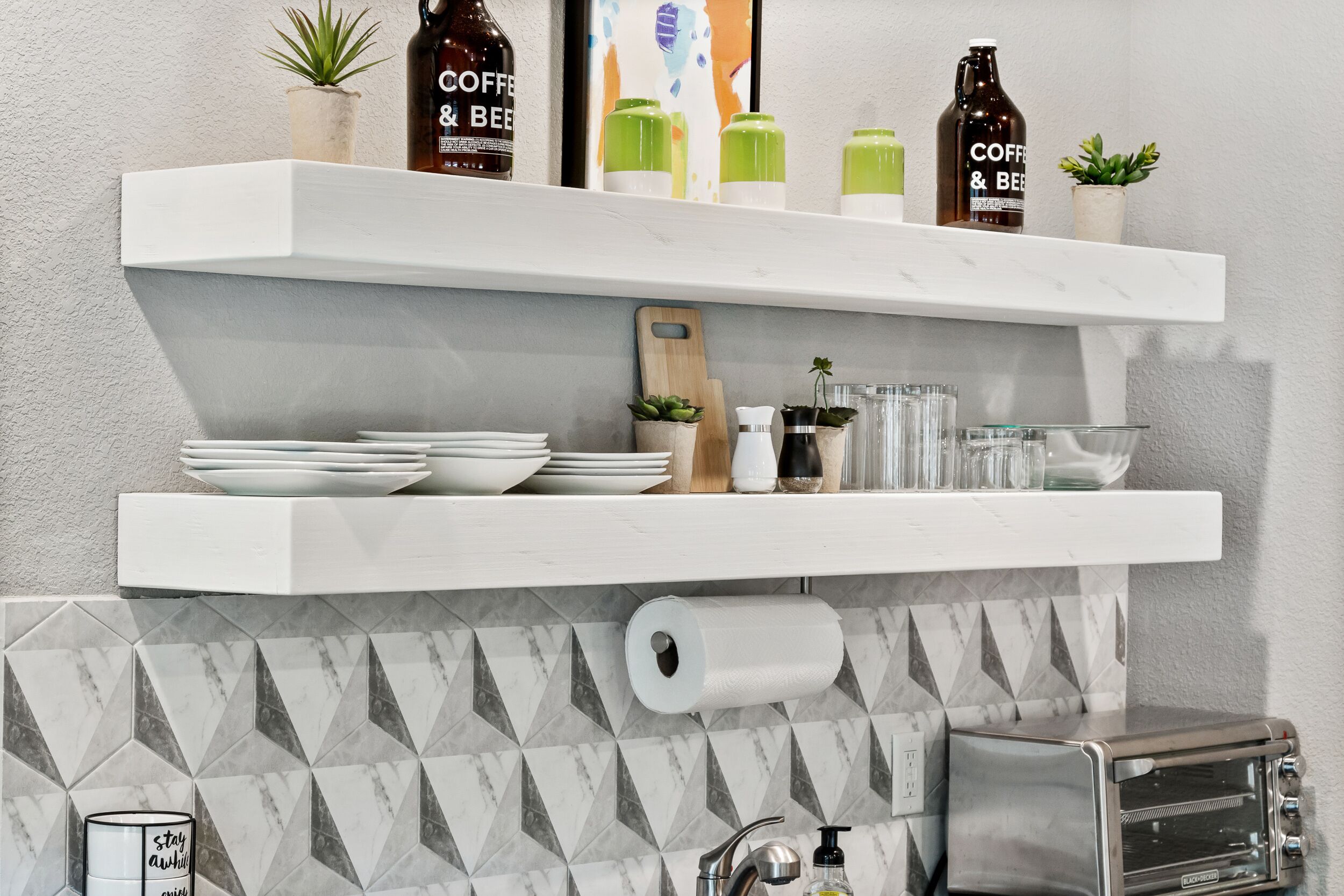 A kitchen with white shelves holding kitchenware, a roll of toilet paper, and a toaster.