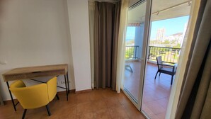 Un balcone con vista sulla città, una sedia gialla e un tavolo con piano in legno.