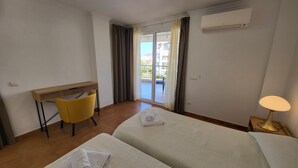 Camera d'albergo con due letti, una scrivania, una sedia, una lampada e un condizionatore d'aria.