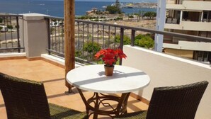 Un balcone con sedie in vimini e un tavolo, con vista sulla costa.