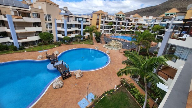 Un resort con diverse piscine, un giardino curato e moderni edifici con balconi.