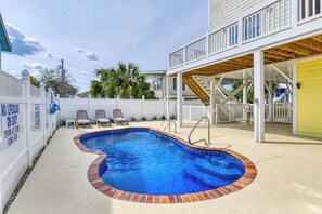 Ein Garten mit Swimmingpool, einer überdachten Terrasse und einem weißen Zaun mit Warnschildern.