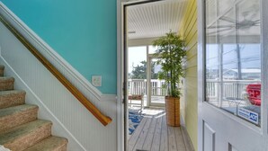 Una escalera conduce a un porche cubierto con una planta en maceta y vistas al exterior.