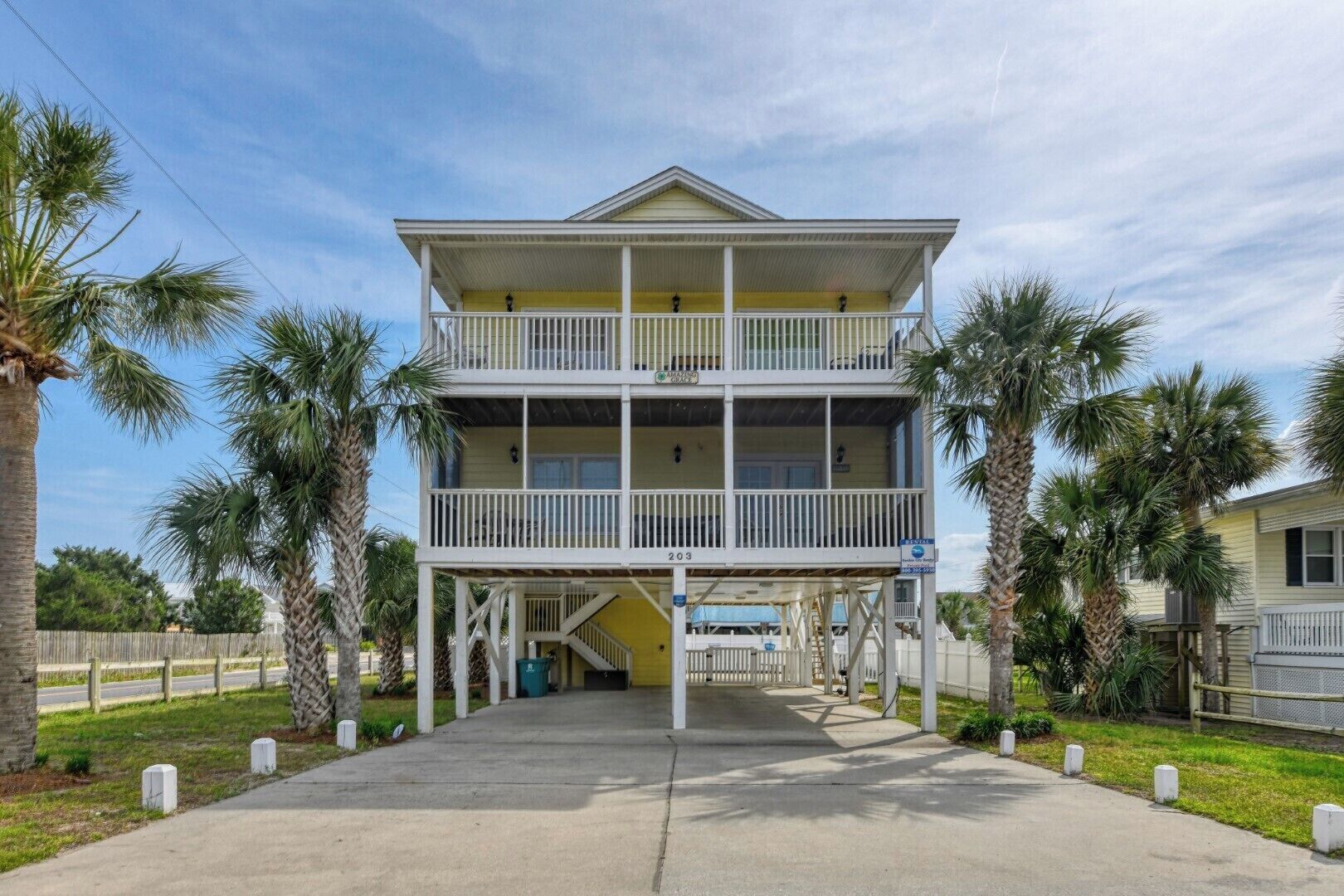 A two-story building with a balcony on the upper floor, a covered entrance, and a clear sky.