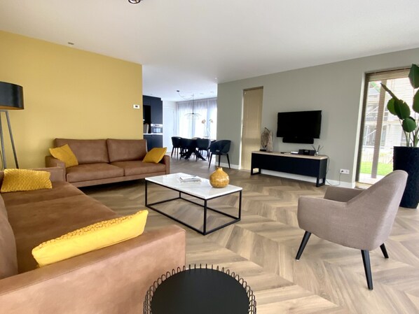 A modern living room with a sofa, armchair, coffee table, and a TV. - Oesterdam Resort by Interhome (Tholen)