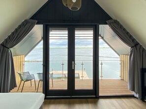A room with a large sliding glass door leading to an outdoor deck with a view of a body of water. - Oesterdam Resort by Interhome (Tholen)