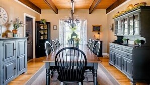 A dining room with a wooden table and chairs, a chandelier, and cabinets.