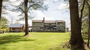 A large two-story house with a well-maintained lawn and trees in the foreground.