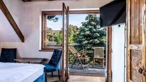 A bedroom with a bed, a blue chair, a table, and a TV.