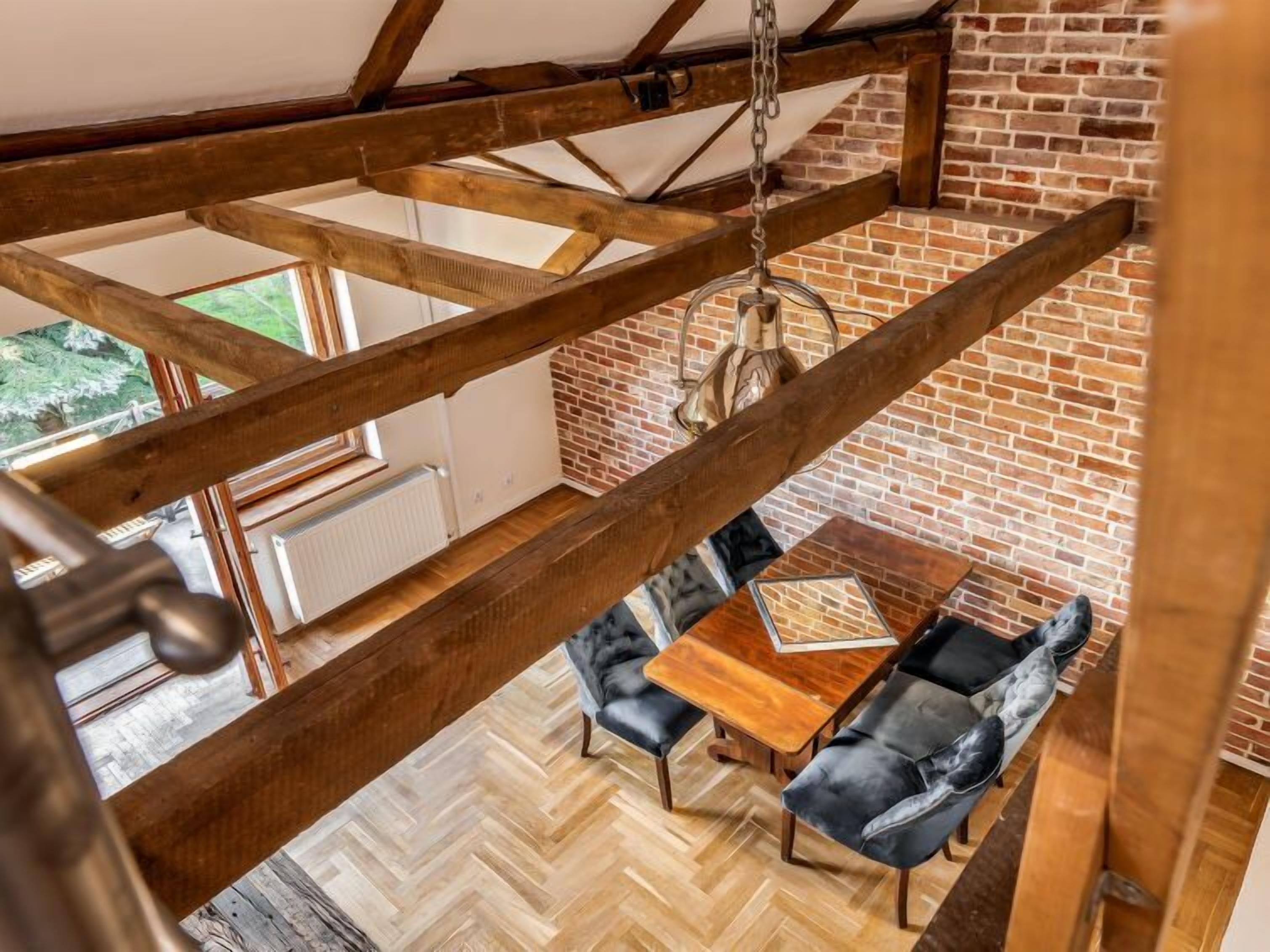 Une pièce de style « loft » avec des poutres en bois apparentes, un parquet à motifs en chevrons, un mur en briques et un luminaire suspendu.