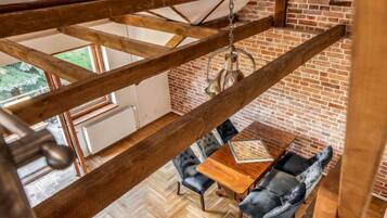 Une pièce de style « loft » avec des poutres en bois apparentes, un parquet à motifs en chevrons, un mur en briques et un luminaire suspendu.