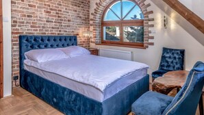 A bedroom with a brick wall, a large bed, a wooden ceiling, and a window with a view.