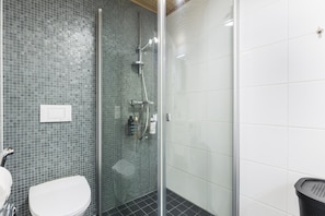 Een moderne badkamer met een douchecabine van glas, een wit toilet en een wastafel.