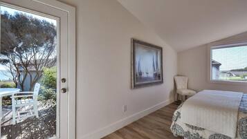 A bedroom with a bed, a chair, a painting, and a view of the outdoors.