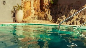 Ein Swimmingpool mit klarem Wasser, einer Steinmauer und einer Metallleiter.