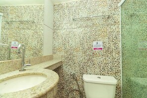 A bathroom with a granite sink, a toilet, and a shower area.