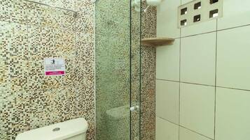 Un baño con pared de mosaicos, cabina de ducha de vidrio y un inodoro.