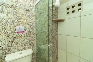 A bathroom with a mosaic tile wall, a glass shower enclosure, and a toilet.