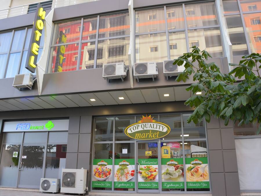 A hotel with a 'HOTEL' sign, a 'FED invest' sign, and a 'TOP QUALITY market' sign.