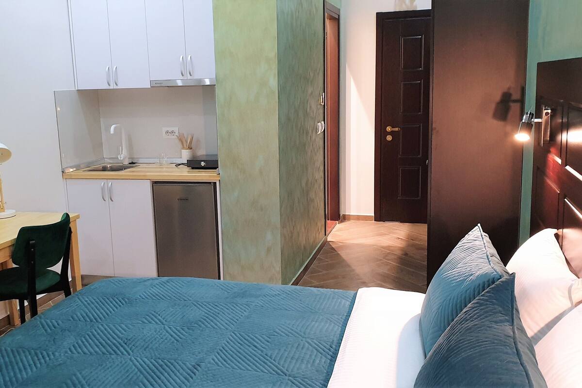 Une petite chambre comprenant un lit, un bureau et une kitchenette.