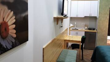 Une petite cuisine équipée d’un réfrigérateur, d’un four à micro-ondes et d’un évier. La pièce comprend également une table en bois et un banc.
