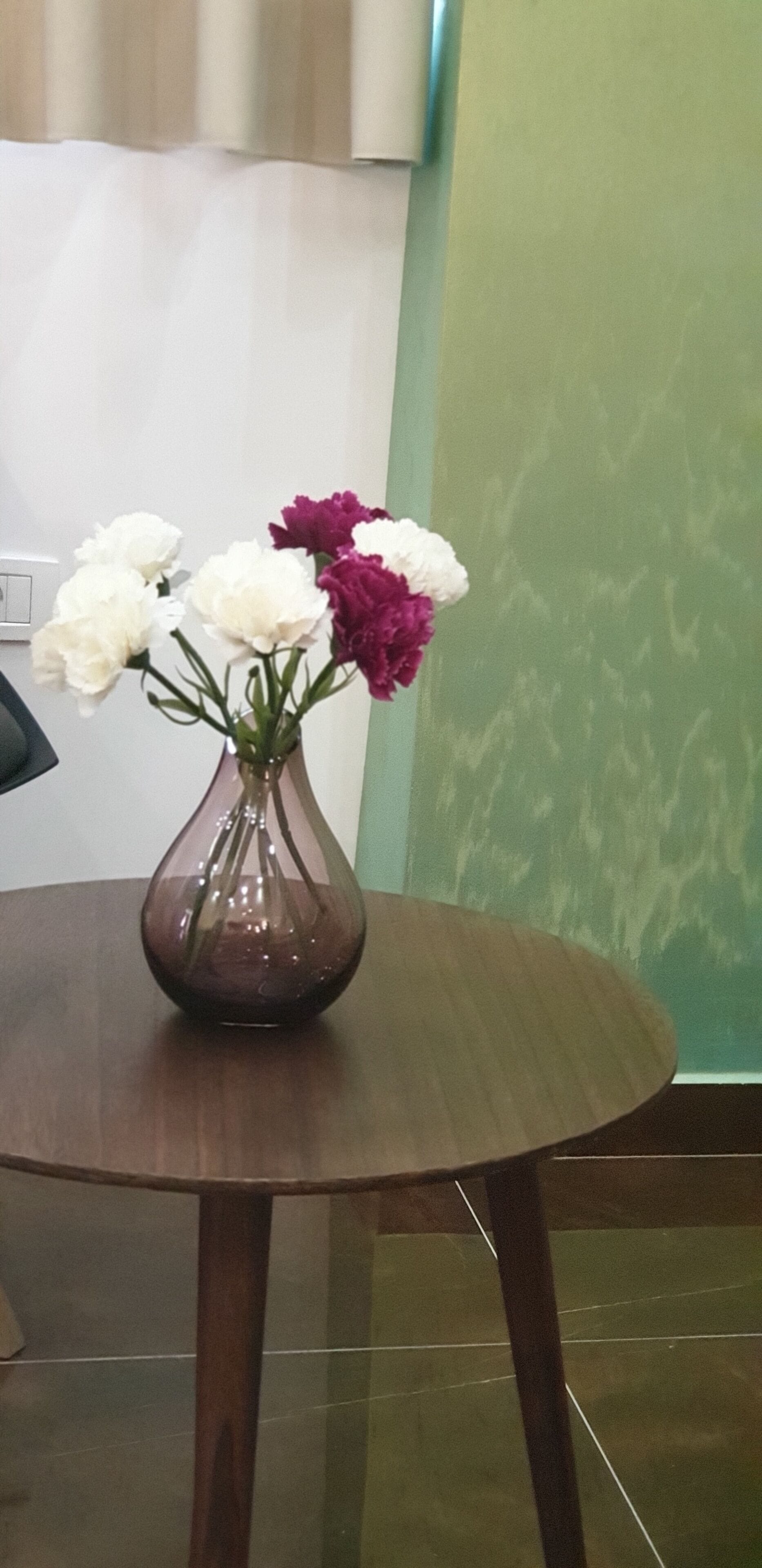 Una mesa redonda de madera con un jarrón de flores.