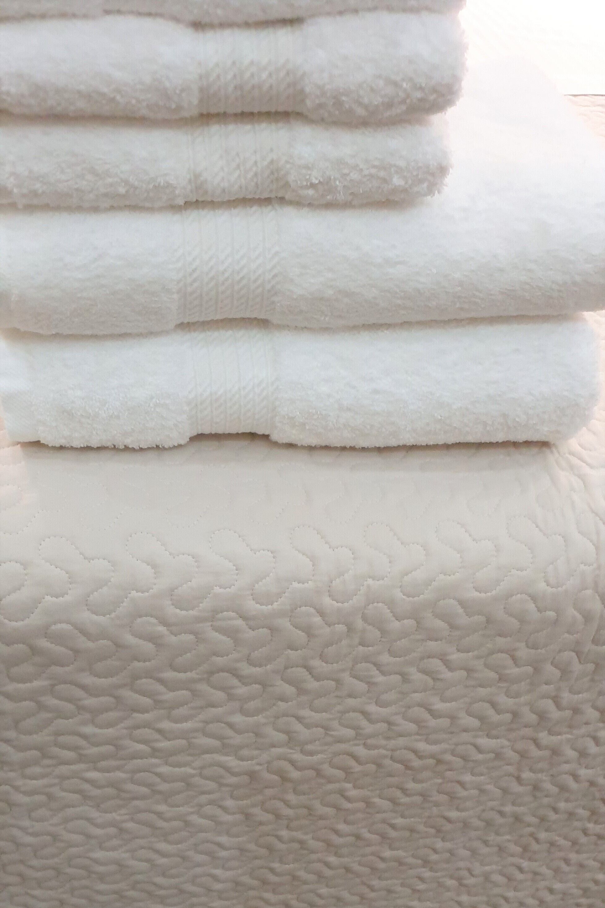 A stack of white towels on a textured white surface.