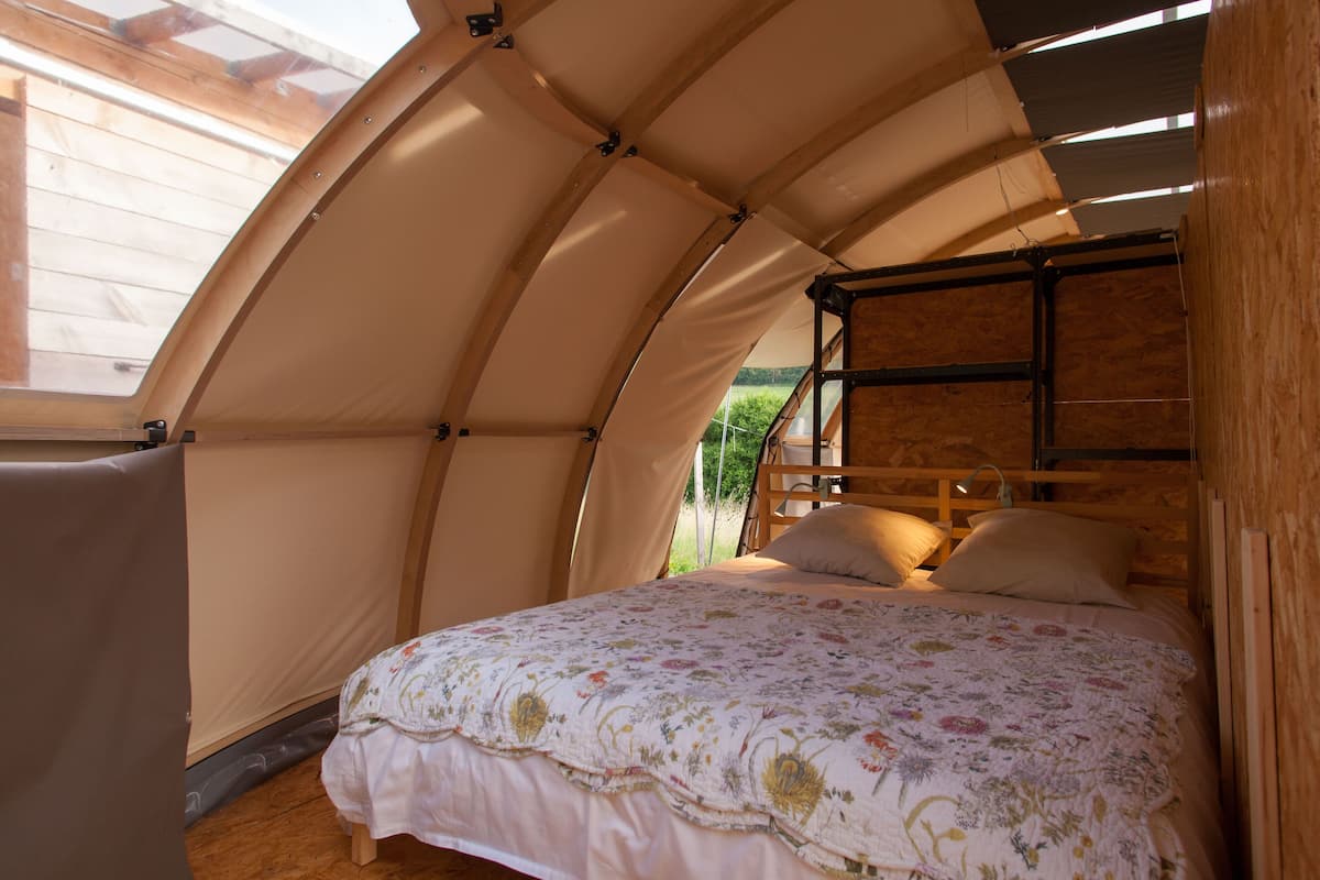 Ein Zelttyp-Zimmer mit Bett, Holzbalken und einem Dachfenster.