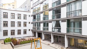 Un immeuble à plusieurs étages doté de balcons, de grandes fenêtres et d’une cour intérieure avec une aire de jeux.