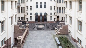 Un immeuble à plusieurs étages doté d’une cour intérieure, d’un escalier en pierre et d’un banc.