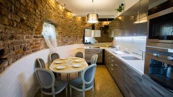A modern kitchen with a stone wall, a dining table set for four, and a built-in oven.