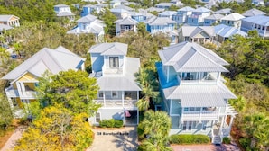 A residential area with multiple houses, including a two-story house with a balcony and a flag. - Fall Break Dates Filling Fast! | Seacrest | Pet Friendly (Inlet Beach)