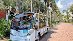 A white bus with a blue route sign labeled "Route E" parked on a brick pathway. - Fall Break Dates Filling Fast! | Seacrest | Pet Friendly (Inlet Beach)