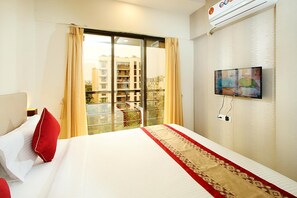 A hotel room with a large bed, a TV mounted on the wall, and a balcony with curtains. - Mumbai House Luxury Apartment (Mumbai)