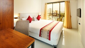 Una habitación de hotel con una cama grande, un escritorio de madera y un televisor montado en la pared.