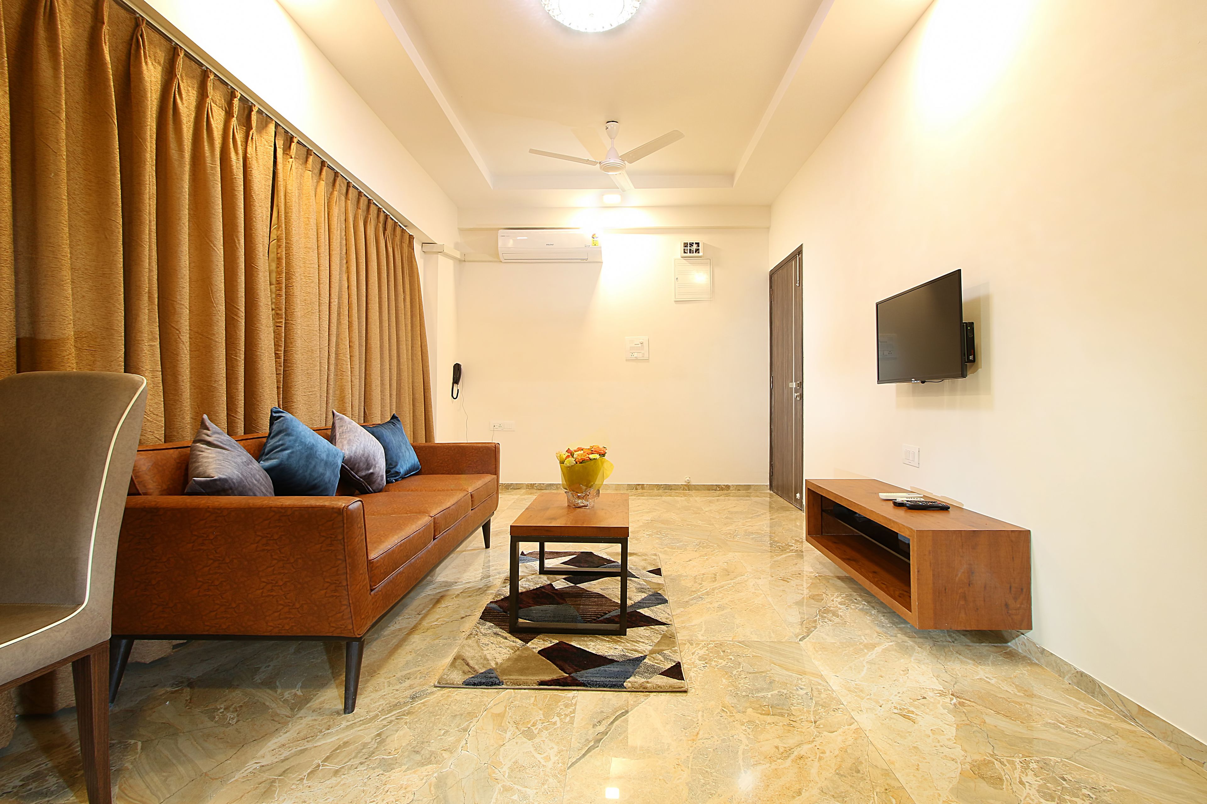 A living room with a sofa, a coffee table, a TV, and a ceiling fan.