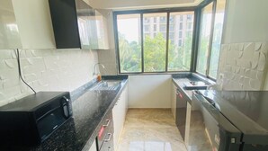 Una cocina moderna con encimera de granito, horno microondas integrado y refrigerador.