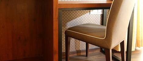 A wooden desk with a television mounted above it, a chair, and a patterned wall.