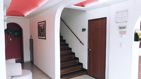 A hallway with a staircase leading to a door marked with the number 106. - Ayenda Palermo Plaza (Bogotá)