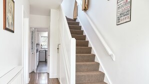 A staircase with carpeted steps leading to a kitchen area. - 16 Austin Avenue (Bromley)