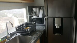 Een keuken met een roestvrijstalen koelkast, een koffiezetapparaat, een magnetron en een afwasschaal.