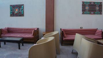 A patio area with two sofas and wicker chairs, a small table, and two wall-mounted decorative panels.