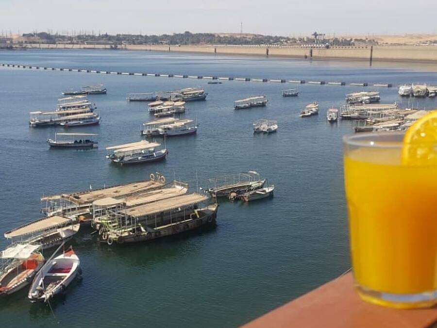 Uma marina com diversos barcos atracados, céu claro e uma linha de costa distante.