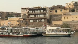 A row of boats docked at a harbor with buildings in the background. - Villa Misk (Aswan)
