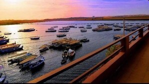 A river with boats docked along the banks, a bridge with a railing, and a distant shoreline. - Villa Misk (Aswan)