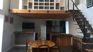 Un loft espacioso con techo alto, un entrepiso, una zona de cocina y una escalera.