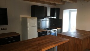 Una cocina con encimeras de madera, un refrigerador blanco, una estufa y armarios negros.