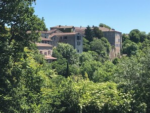 A historic building with multiple stories, surrounded by lush greenery.