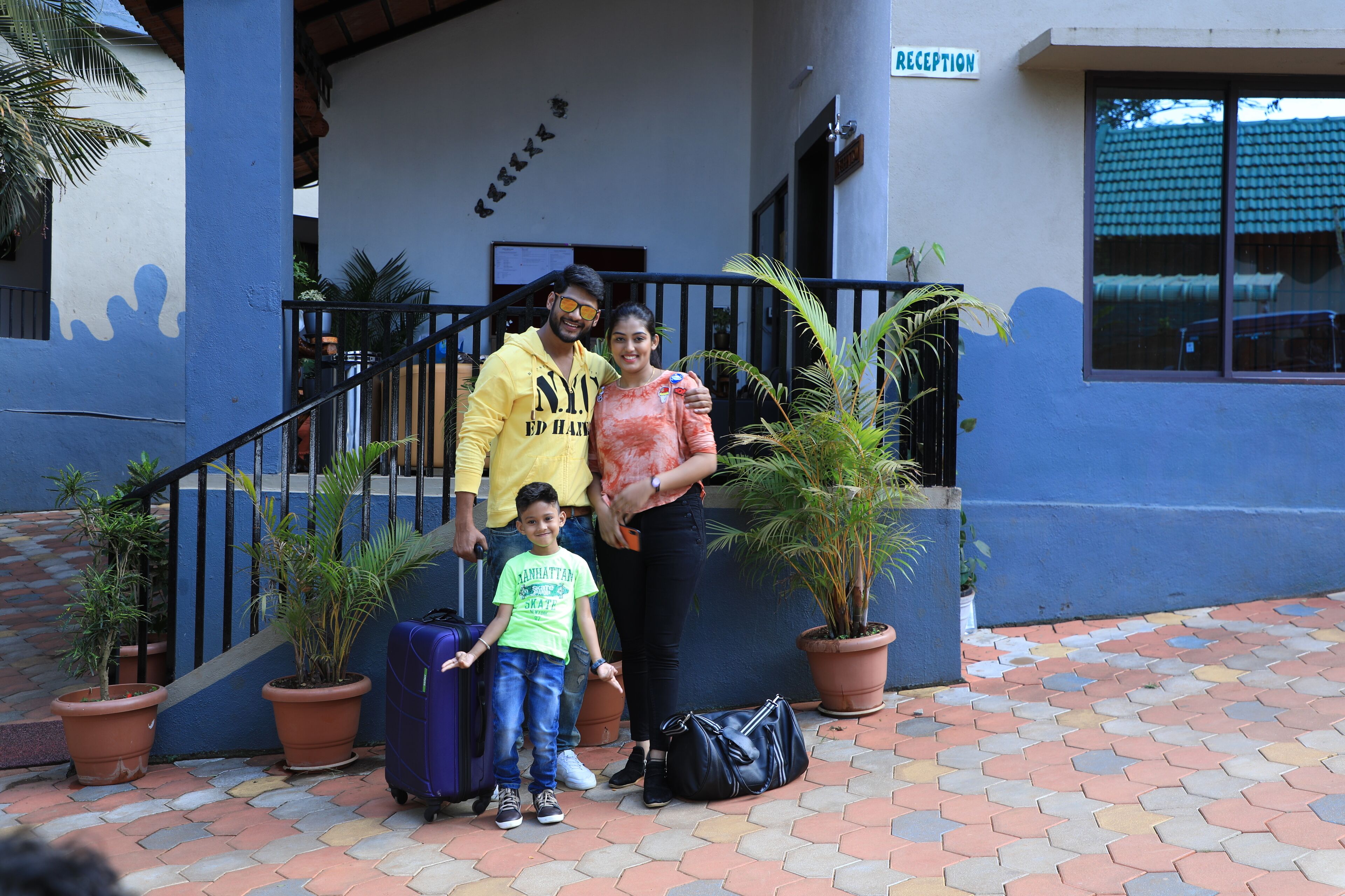 A family with luggage in front of a building with a reception sign.