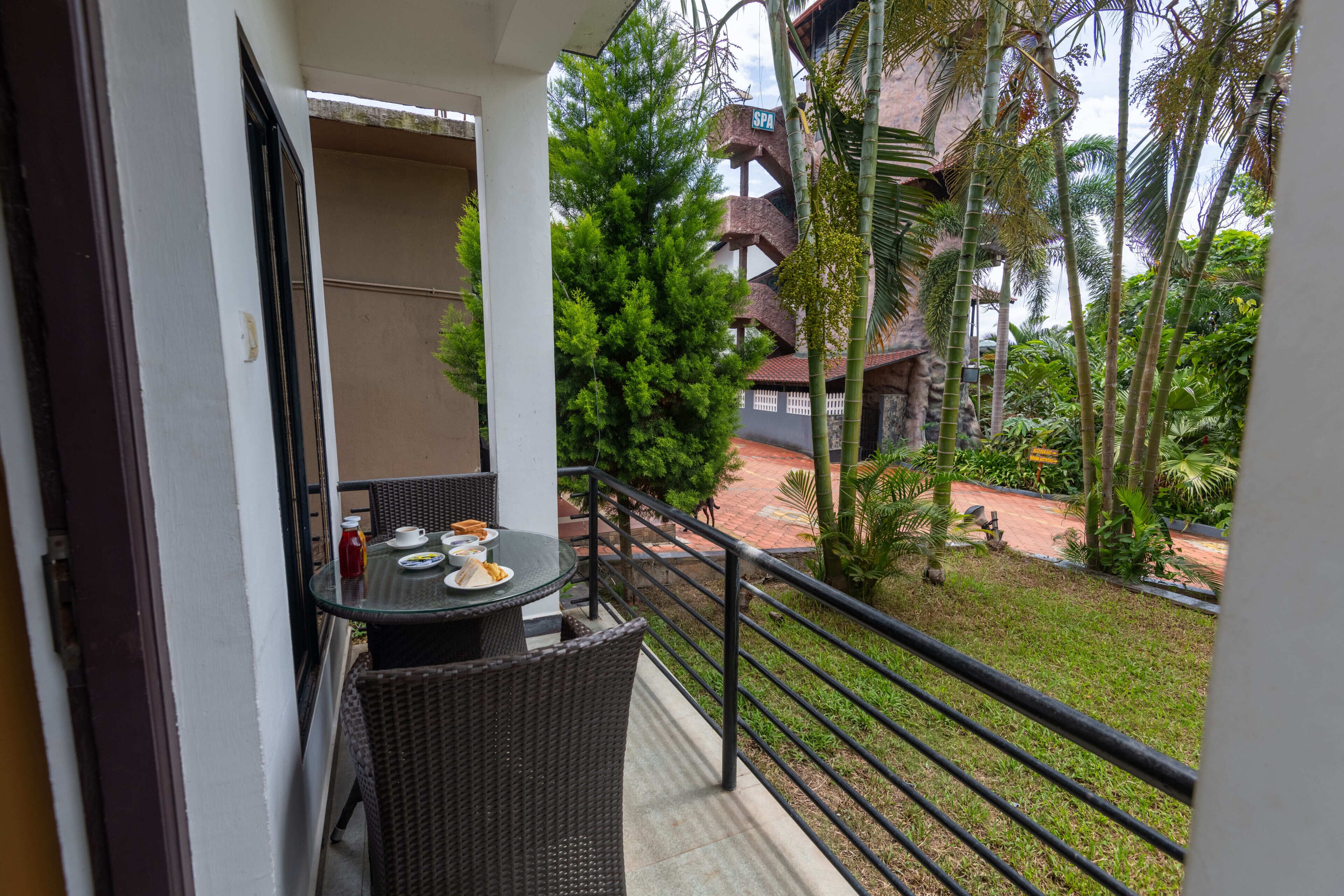 A balcony with wicker furniture, a table with plates and a bottle, and a view of a building with a 'SPA' sign.